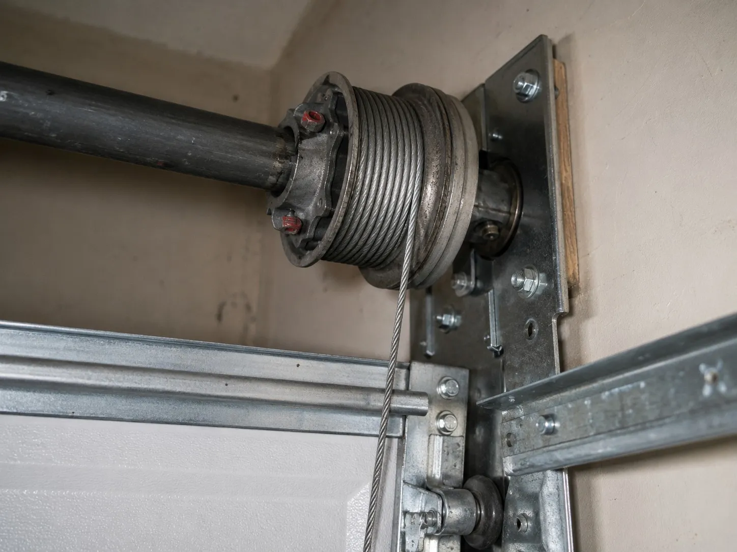 Grooved cable drum mounted on a garage door torsion shaft.