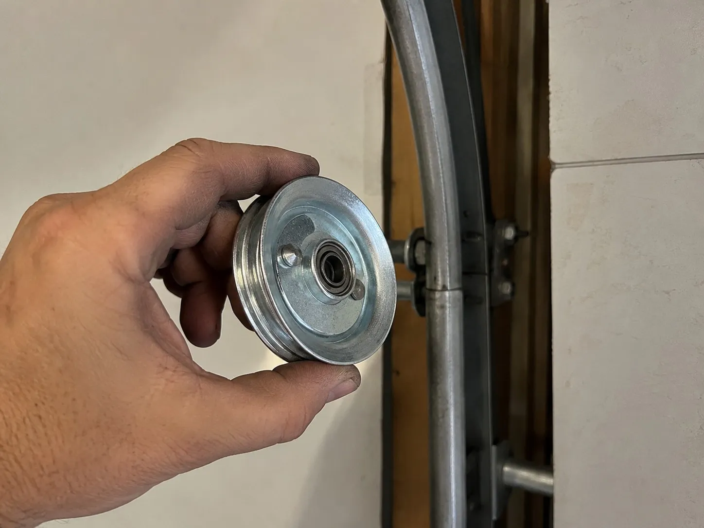 New pulley sheave installed on a garage door extension spring system.