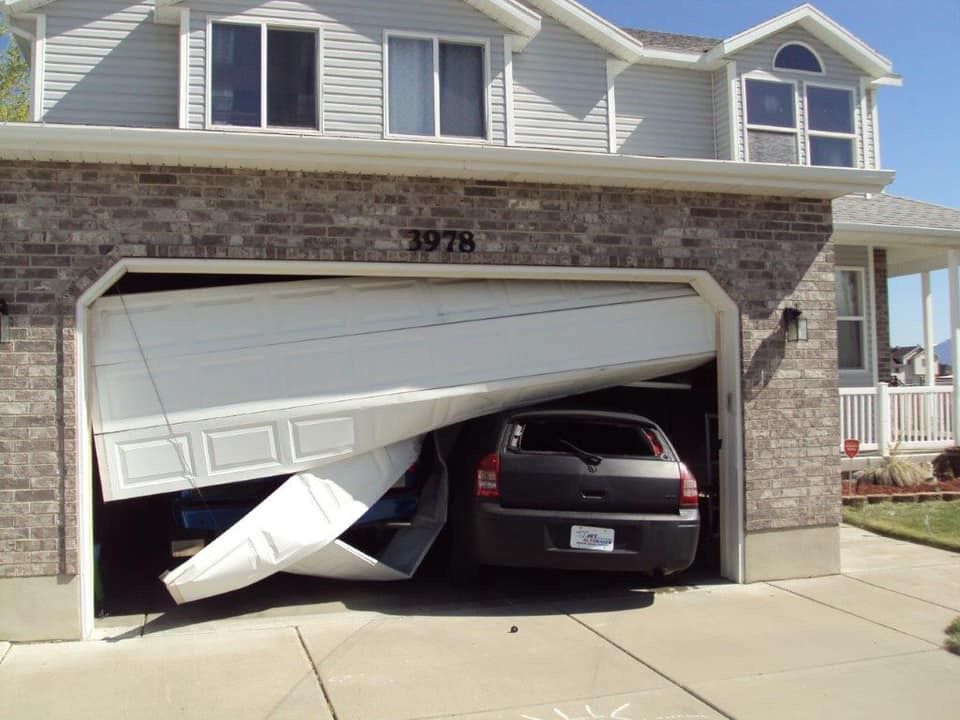 Car crashed into a residential garage door needing emergency repair.