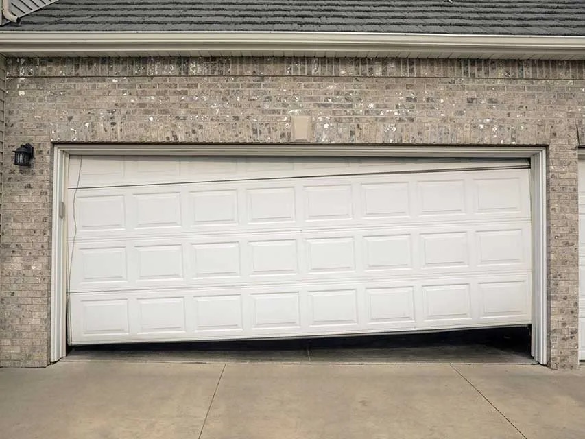 Garage door off its track and sagging on the exterior.
