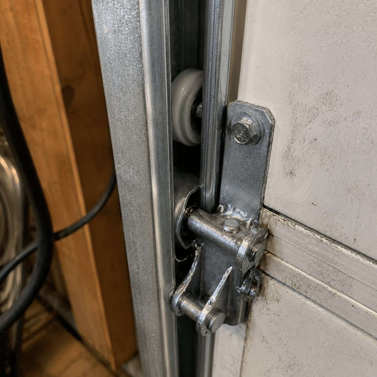 The same track and hinge cleaned and lubricated with a fresh roller, serviced by Boost Garage Doors.