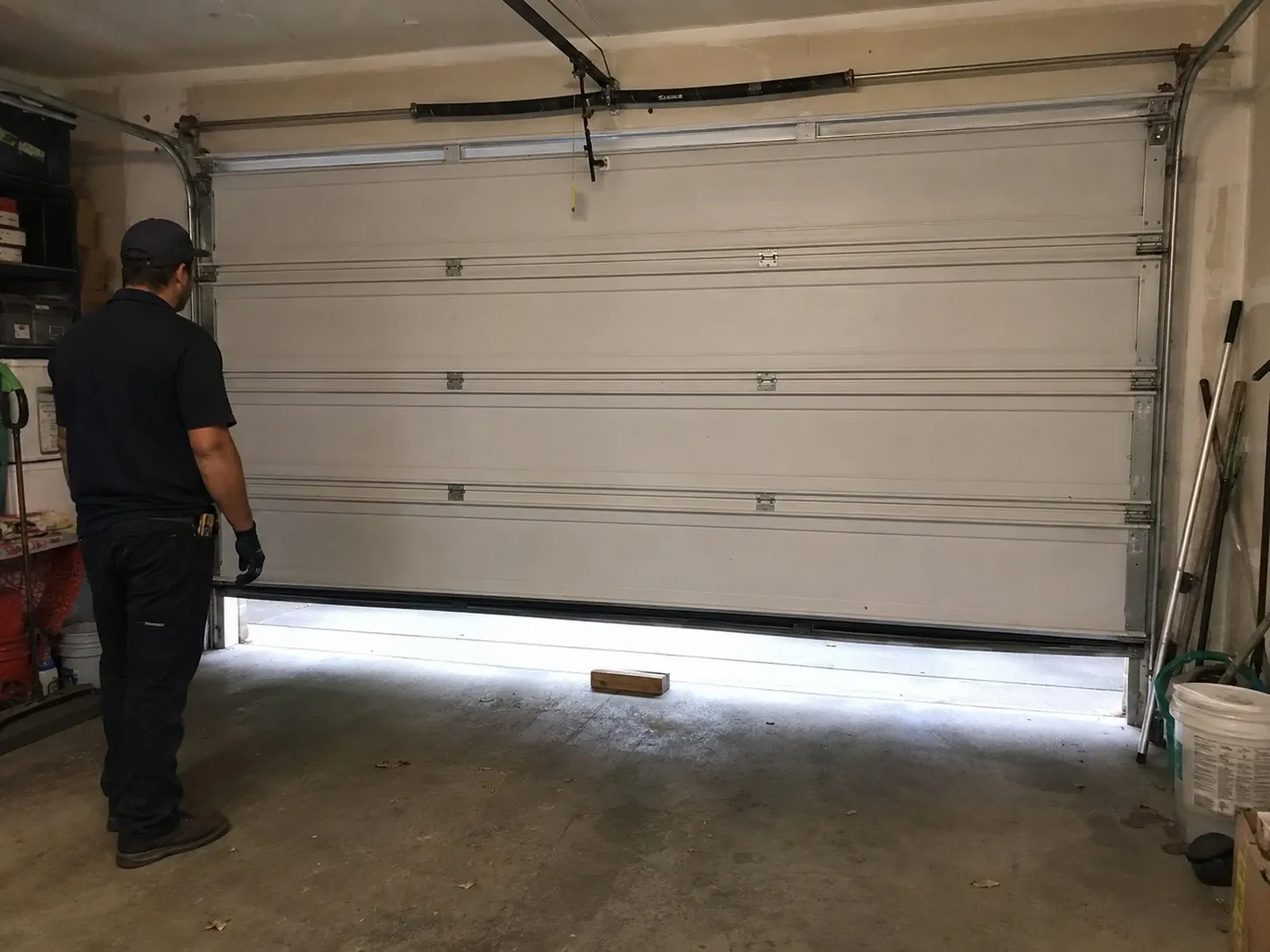 Technician testing the auto-reverse safety feature on a garage door.