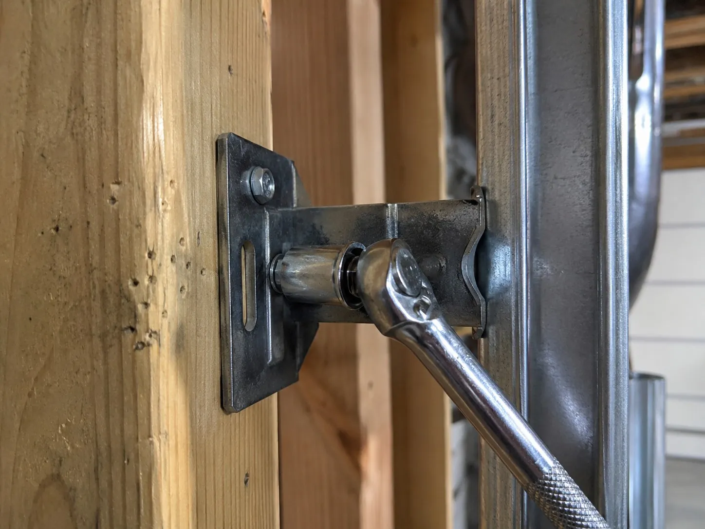 Lag bolts anchoring a garage door opener bracket to the ceiling framing.