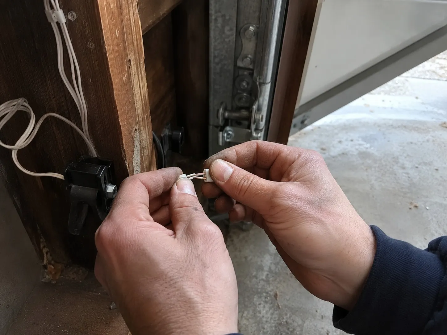 Technician repairing the low voltage wiring for a garage door safety sensor.
