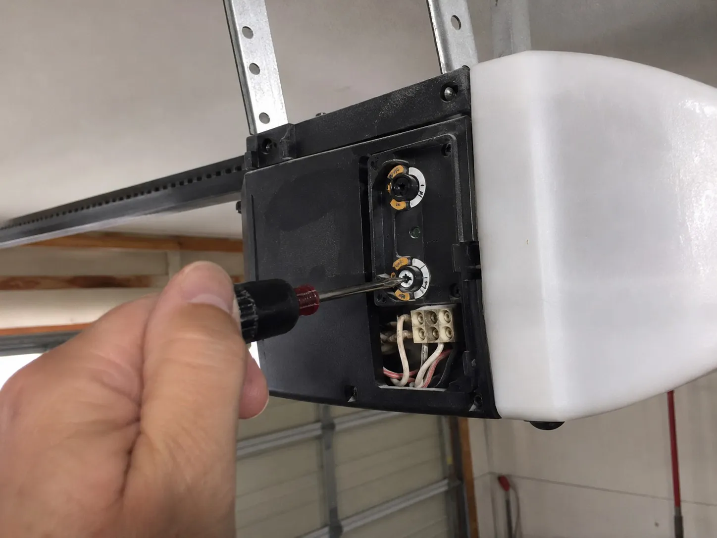 Technician adjusting the force and travel limit dials on a garage door opener.