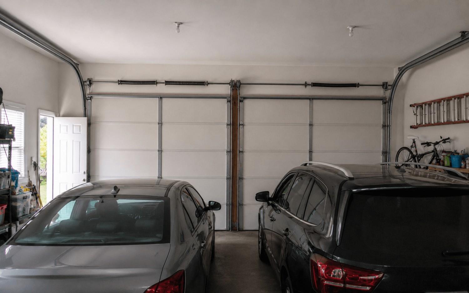 A wide view of a double garage with a snapped spring on the torsion bar above the doors.