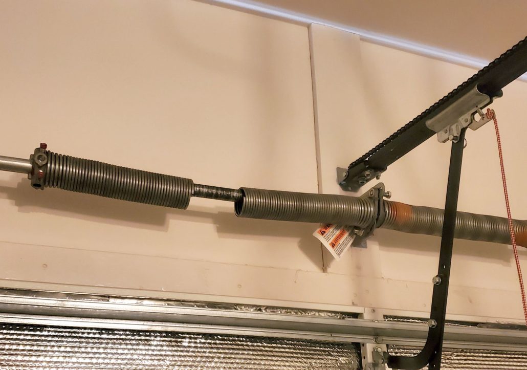 Broken garage door torsion spring with a visible gap above the door.