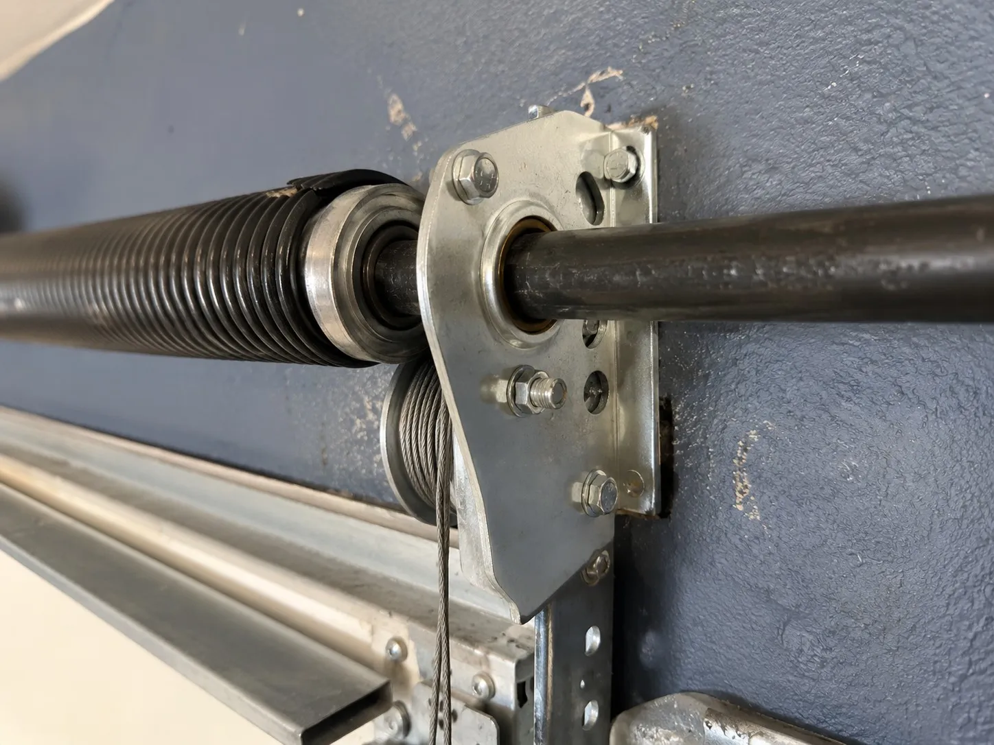 End bearing plate anchoring a garage door torsion shaft at the header.
