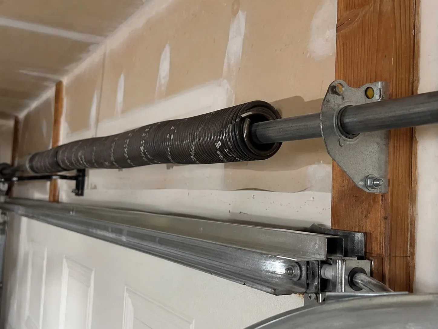 Steel torsion bar shaft spanning the header above a garage door.